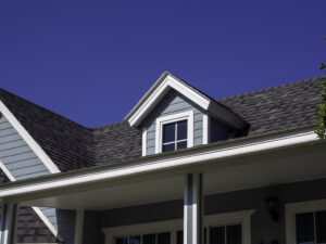 White vintage windows, little room decoration on the roof of the big wooden house pastel green color on blue sky background, view from outside.